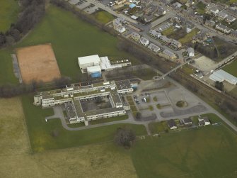 Oblique aerial view centred on the school and the footbridge, taken from the SE.