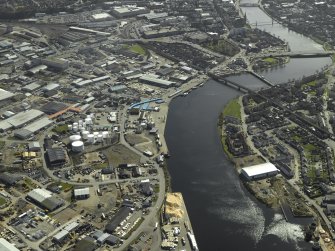 General oblique aerial view of the town centred on the shipyard with the railway viaduct, road bridges and suspension bridge adjacent, taken from the N.