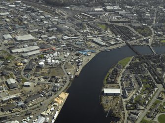 General oblique aerial view of the town centred on the shipyard with the railway viaduct and road bridge adjacent, taken from the NW.