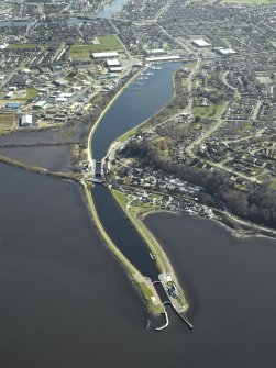 General oblique aerial view centred on the Caledonian Canal, locks, swing bridge and canal basins, taken from the NW.