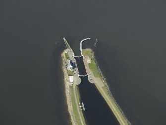Oblique aerial view centred on the lock, house, piers and beacons, taken from the SE.
