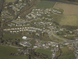 Oblique aerial view of the village centred on the school, church and burial-ground, taken from the SW.