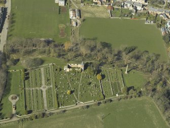 Oblique aerial view centred on the chapel, burial-ground and monument, taken from the SE.
