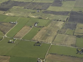 Oblique aerial view of the village centred on the pattern of dispersed buildings and layout of regular fields, taken from the NW.