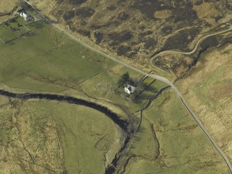 Oblique aerial view centred on the church and the remains of the broch with the manse adjacent, taken from the ESE.