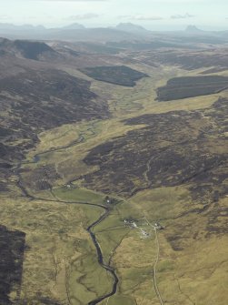 General oblique aerial view looking along Strath Cuileamach centred on the church, manse and remains of the broch, taken from the E.