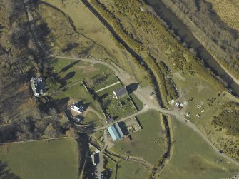 Oblique aerial view centred on the church, burial-ground, manse, road bridge and farmstead, taken from the S.