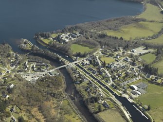 General oblique aerial view of the village centred on the road bridges, swing bridge, locks, abbey and schools, taken from the NW.