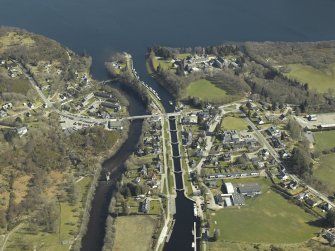 General oblique aerial view of the village centred on the road bridges, swing bridge, locks, abbey and schools, taken from the W.