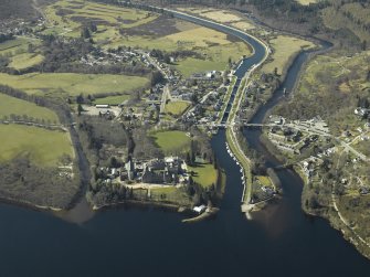 General oblique aerial view of the village centred on the road bridges, swing bridge, locks, abbey and schools, taken from the ENE.