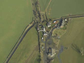 Oblique aerial view centred on station buildings, footbridge and road bridge, taken from the SSW.
