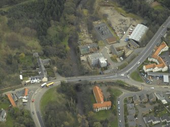 Oblique aerial view centred on the road bridge, abattoir, mill, granary and inn, taken from the W.