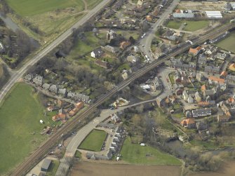 Oblique aerial view of the village centred on the road bridges, railway viaduct and church, taken from the ENE.