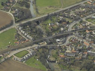 Oblique aerial view of the village centred on the road bridges, railway viaduct and church, taken from the NE.