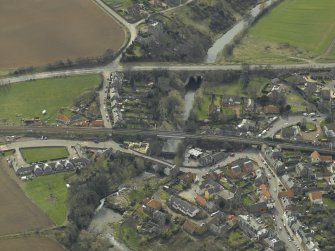 Oblique aerial view of the village centred on the road bridges, railway viaduct and church, taken from the NNE.