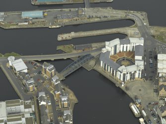 Oblique aerial view centred on the swing bridge, road bridge, harbour, office and dry dock, taken from the SW.