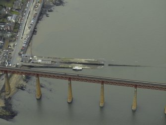 Oblique aerial view centred on the pier, slipway and lifeboat station with the railway bridge adjacent, taken from the NE.