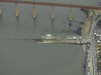 Oblique aerial view centred on the pier, slipway and lifeboat station with the railway bridge adjacent, taken from the SW.
