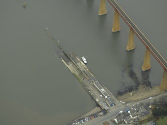 Oblique aerial view centred on the pier, slipway, lifeboat station and beacon with the railway bridge adjacent, taken from the S.