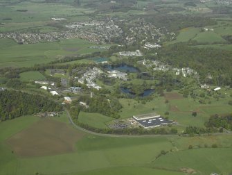 General oblique aerial view centred on the university, library, auditorium, halls of residence, bridge and factory with the country house adjacent, taken from the ESE.