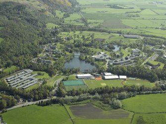 General oblique aerial view centred on the university, library, auditorium, halls of residence, bridge and factory with the country house adjacent, taken from the NW.