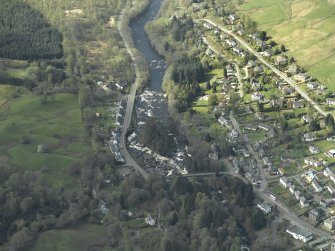 Oblique aerial view of the village centred on the road bridge, taken from the NE.