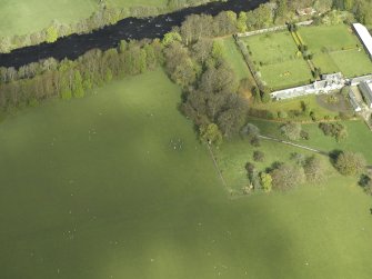 Oblique aerial view centred on the remains of the stone circle with the walled garden and greenhouse adjacent, taken from the SE.