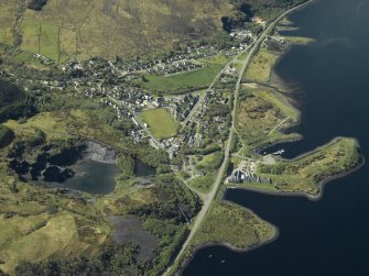 Oblique aerial view of the village centred on the harbour, slate quarries and remains of the fort, taken from the NE.
