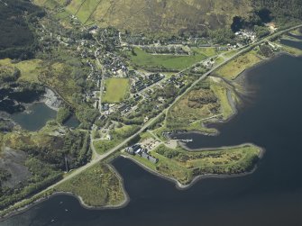 Oblique aerial view of the village centred on the harbour, slate quarries and remains of the fort, taken from the NE.
