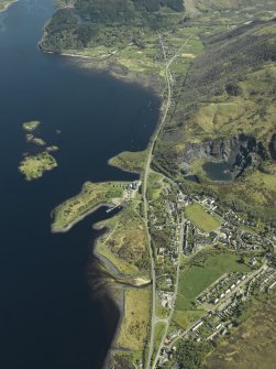 Oblique aerial view of the village centred on the harbour, slate quarries and remains of the fort, taken from the W.