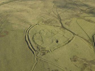 Oblique aerial view centred on the remains of the settlement and earthwork , taken from the SW.