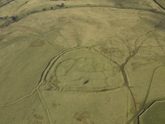 Oblique aerial view centred on the remains of the settlement and earthwork, taken from the NW.