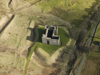 Oblique aerial view centred on Hermitage castle and moat, taken from the W.