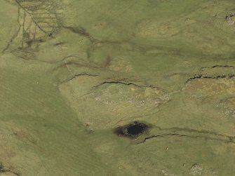 Oblique aerial view centred on the remains of the dun and the shieling huts, taken from the SW.