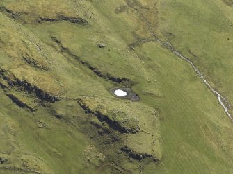 Oblique aerial view centred on the remains of the dun and the shieling huts, taken from the N.