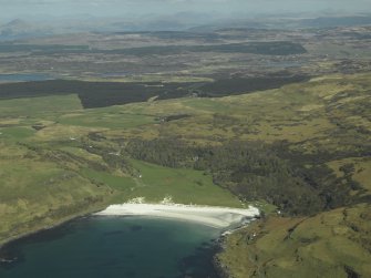 General oblique aerial view of Calgary Bay centred on the remains of the burial-ground with the country house and walled garden adjacent, taken from the SW.