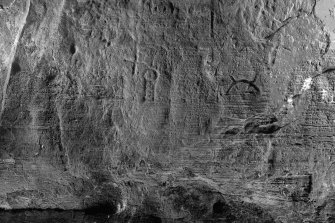 Detail of carving, including cross and crescent and V-rod Pictish symbol on wall of Sculptor's Cave, Covesea (B&W)