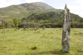 Standing stone with stone circle in background, view from W