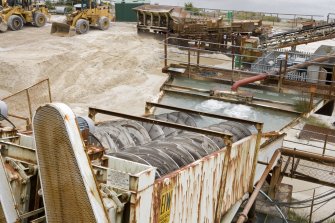 Elevated view of eagle screw, note red pipe in background carrying sand and water from the Allis Chalmers screen. The sand is carried to a higher level, agitated and washed and then sent to the Scrubber.