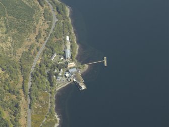 Oblique aerial view centred on the pier and buildings of the Royal Navy Torpedo Station, taken from the SW.