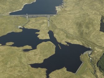 General oblique aerial view centred on the dams, power station and reservoir, taken from the SW.