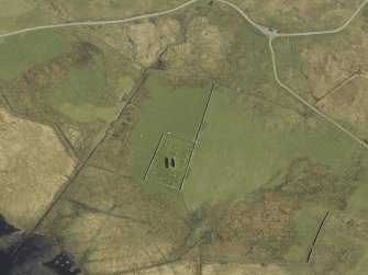 Oblique aerial view centred on the remains of the church and the burial ground, taken from the W.