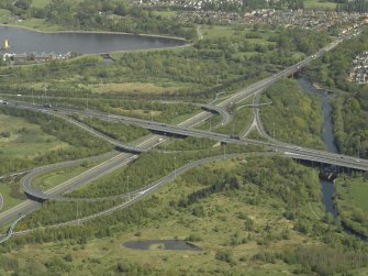 Oblique aerial view centred on the motorway interchange, taken from the NW.