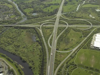 Oblique aerial view centred on the motorway interchange, taken from the NW.