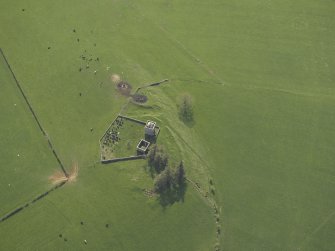 Oblique aerial view centred on the ruins of the tower house and chapel and the graveyard, taken from the E.