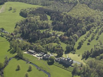 Oblique aerial view centred on the house with stable block and farm adjacent, taken from the NW.
