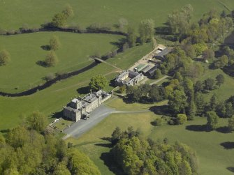 Oblique aerial view centred on the house with stable block and farm adjacent, taken from the SW.
