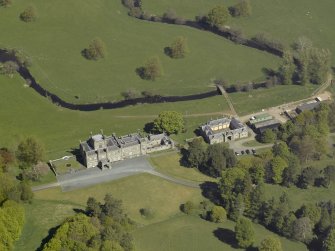 Oblique aerial view centred on the house with stable block and farm adjacent, taken from the S.