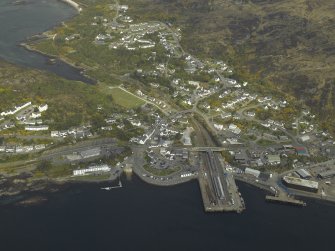 General oblique aerial view of the village centred on the railway station and pier, taken from the S.