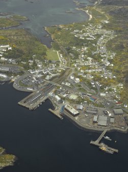 General oblique aerial view of the village centred on the railway station and pier, taken from the SE.